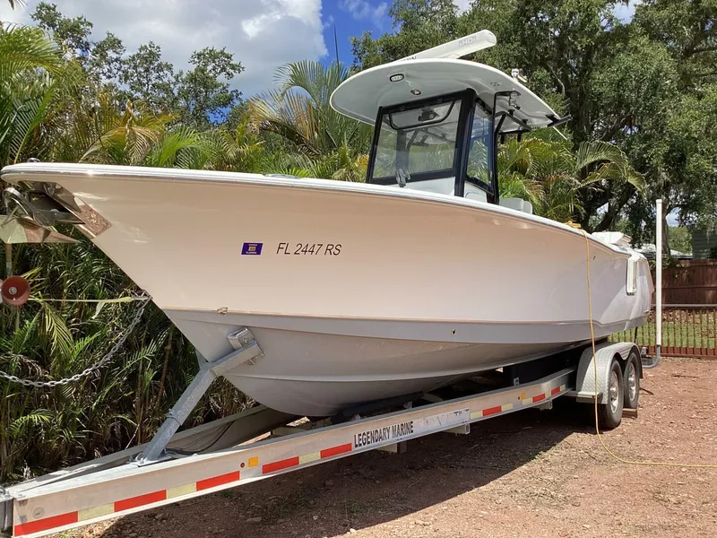 The Image of 2018 Sea Hunt Gamefish 27 boat on trailer, surrounded by lush greenery. - 0