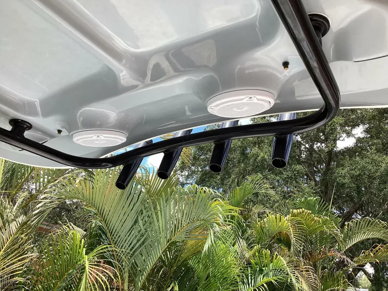 Slide: The Image of 2018 Sea Hunt Gamefish 27 boat roof with rod holders and speakers, surrounded by palm trees. - 35