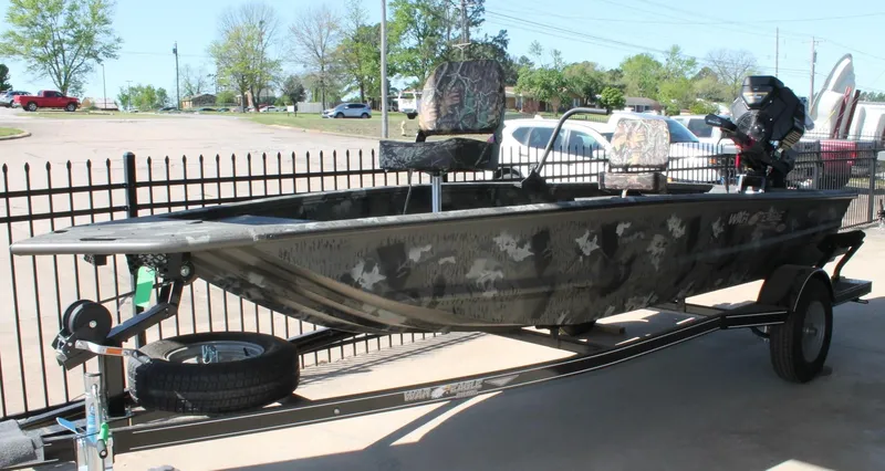 Slide: The Image of 2025 War Eagle 750 Gladiator boat on trailer, camo design, parked outdoors. - 1