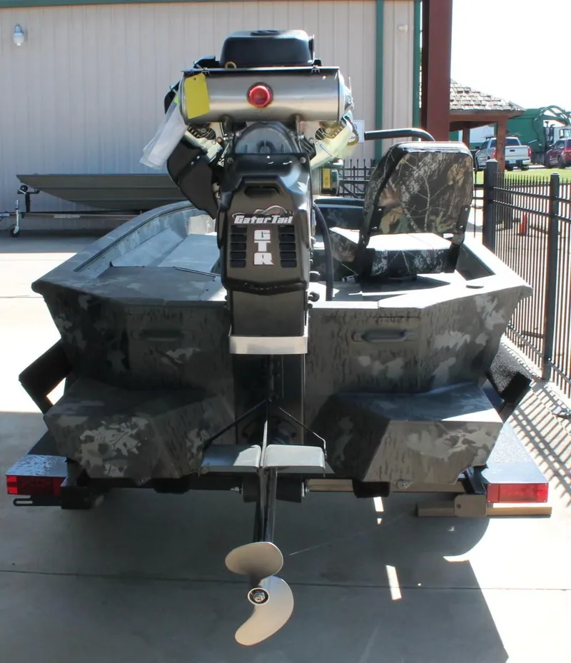 Slide: The Image of 2025 War Eagle 750 Gladiator boat with Gator Tail motor, camo design, parked outdoors. - 12
