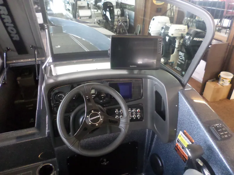 Slide: The Image of 2025 Warrior 238 DC boat dashboard with steering wheel and Garmin display. - 13