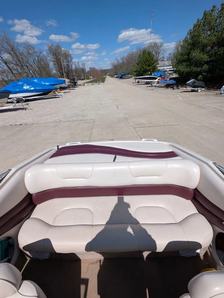 Slide: The Image of 1996 Crownline 182 BR boat interior with white and maroon seating, parked outdoors. - 3