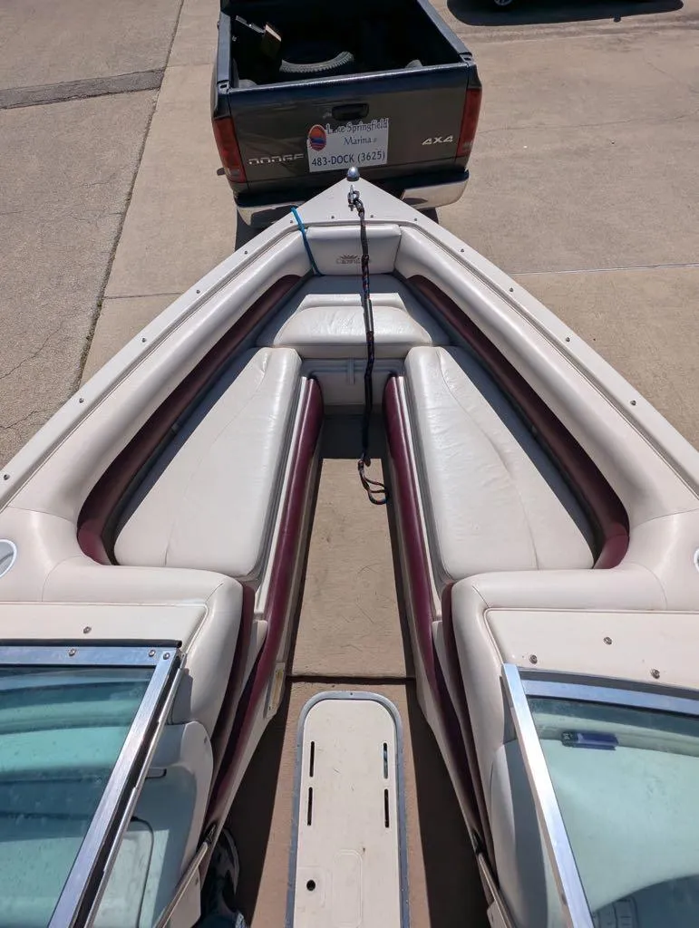 Slide: The Image of 1996 Crownline 182 BR boat interior with white and maroon seating, parked near a truck. - 5