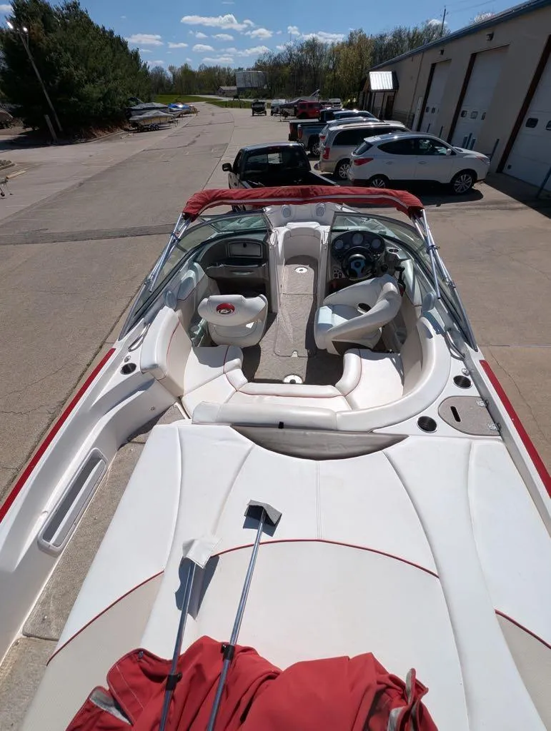 Slide: The Image of 2006 Rinker Captiva 226 boat with white interior, parked outdoors near a garage. - 4
