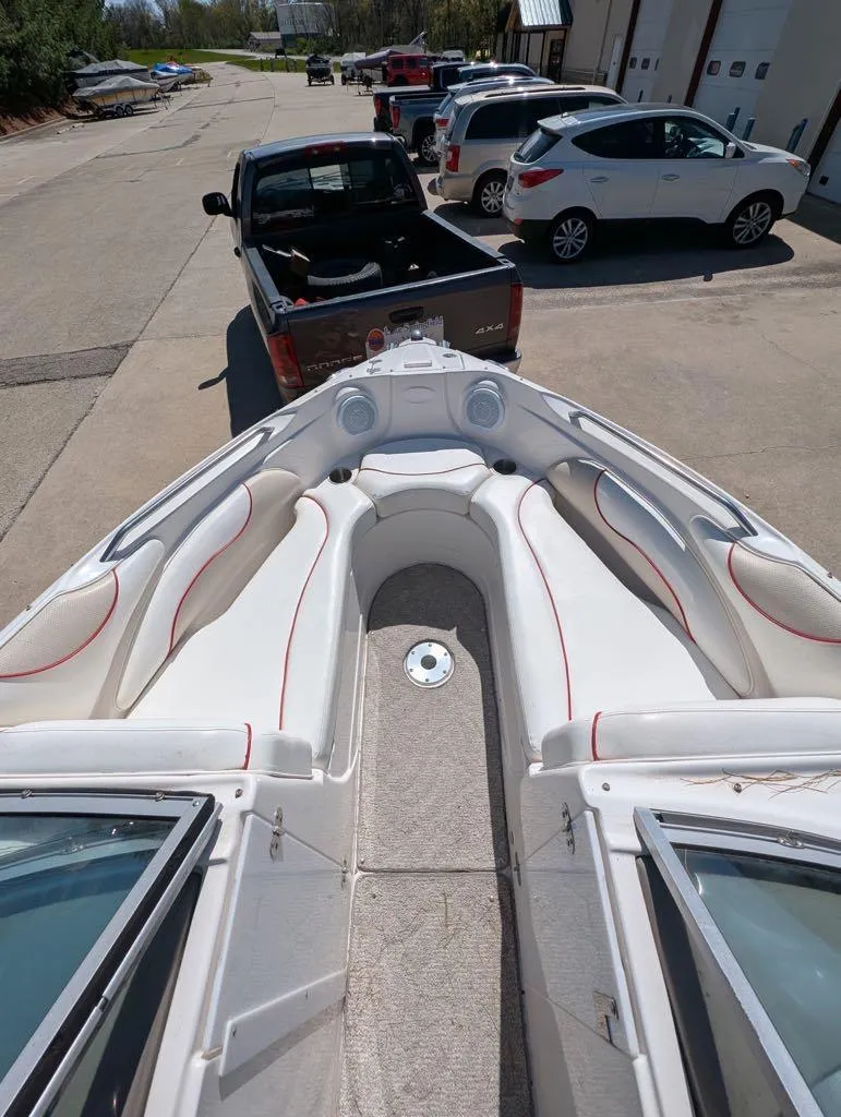 Slide: The Image of 2006 Rinker Captiva 226 boat interior with white seating and red accents, parked near vehicles. - 5
