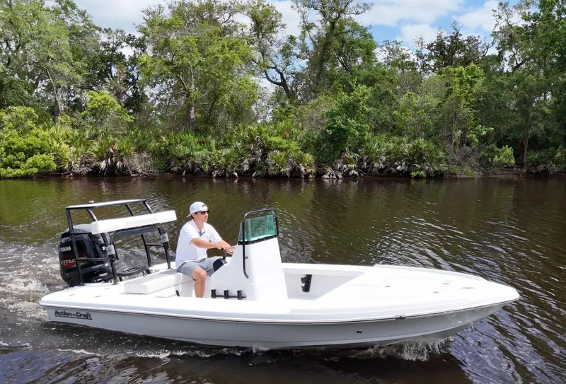 Slide: The Image of 2025 Action Craft 17 Flats boat cruising on a calm river with lush greenery. - 0