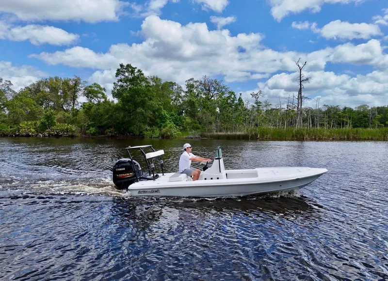 Slide: The Image of 2025 Action Craft 17 Flats boat cruising on a scenic river under a blue sky. - 1