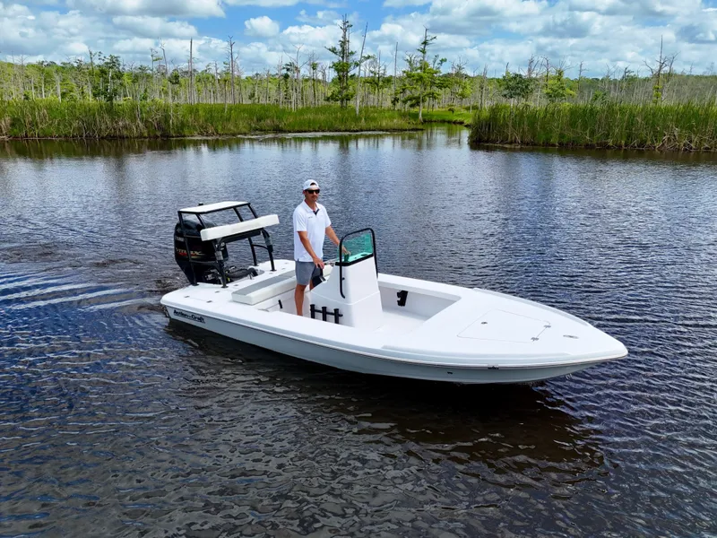 Slide: The Image of 2025 Action Craft 17 Flats boat cruising on a serene lake with lush greenery. - 11