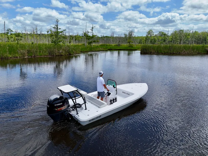 Slide: The Image of 2025 Action Craft 17 Flats boat on a serene lake with lush greenery. - 16