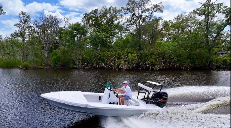 Slide: The Image of 2025 Action Craft 17 Flats boat cruising on a scenic river with lush greenery. - 21