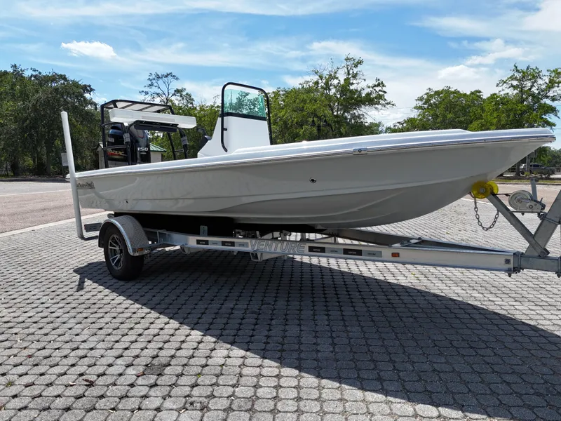 Slide: The Image of 2025 Action Craft 17 Flats boat on trailer, parked on paved surface under clear sky. - 33