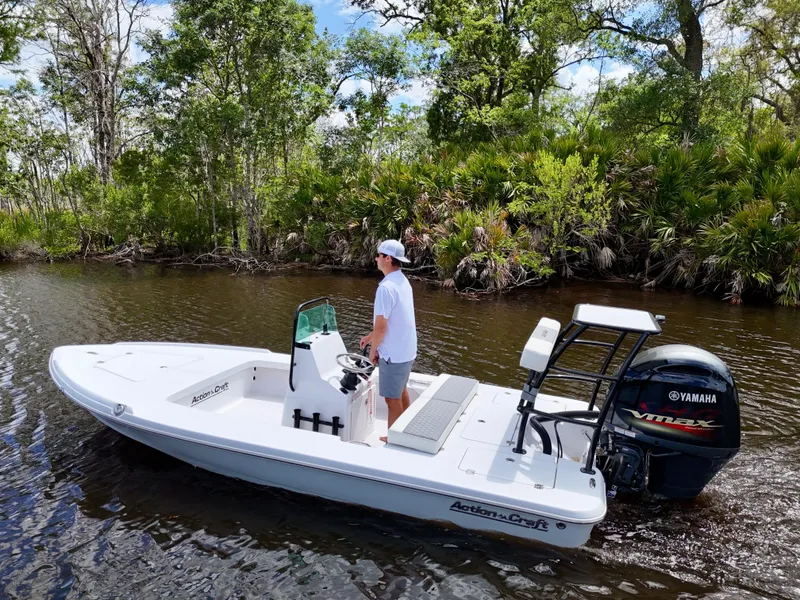 Slide: The Image of 2025 Action Craft 17 Flats boat navigating a scenic river with lush greenery. - 6