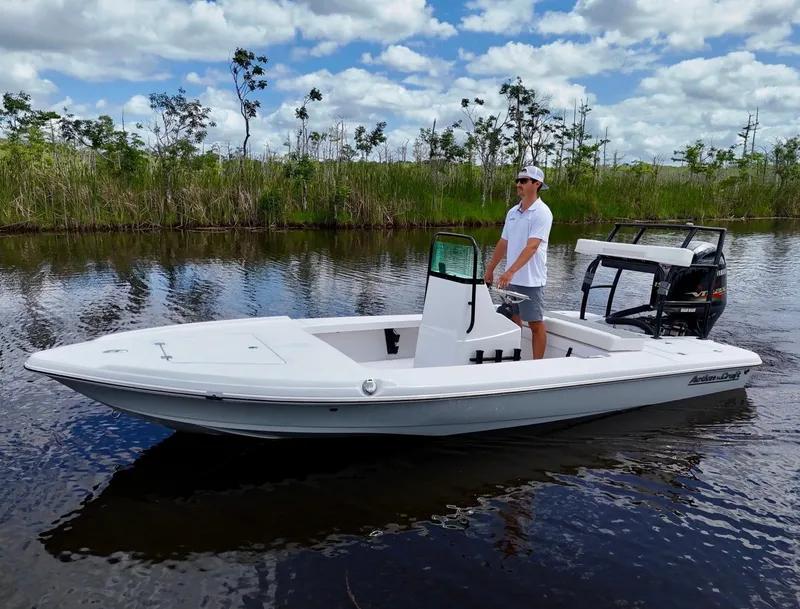 Slide: The Image of 2025 Action Craft 17 Flats boat on calm water, with a person standing at the helm. - 7