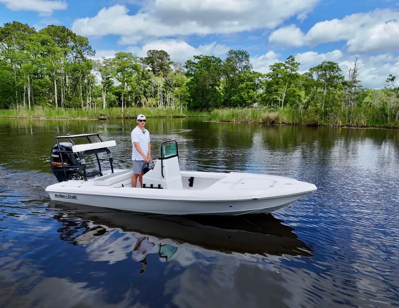 Slide: The Image of 2025 Action Craft 17 Flats boat on a serene lake with lush greenery. - 9