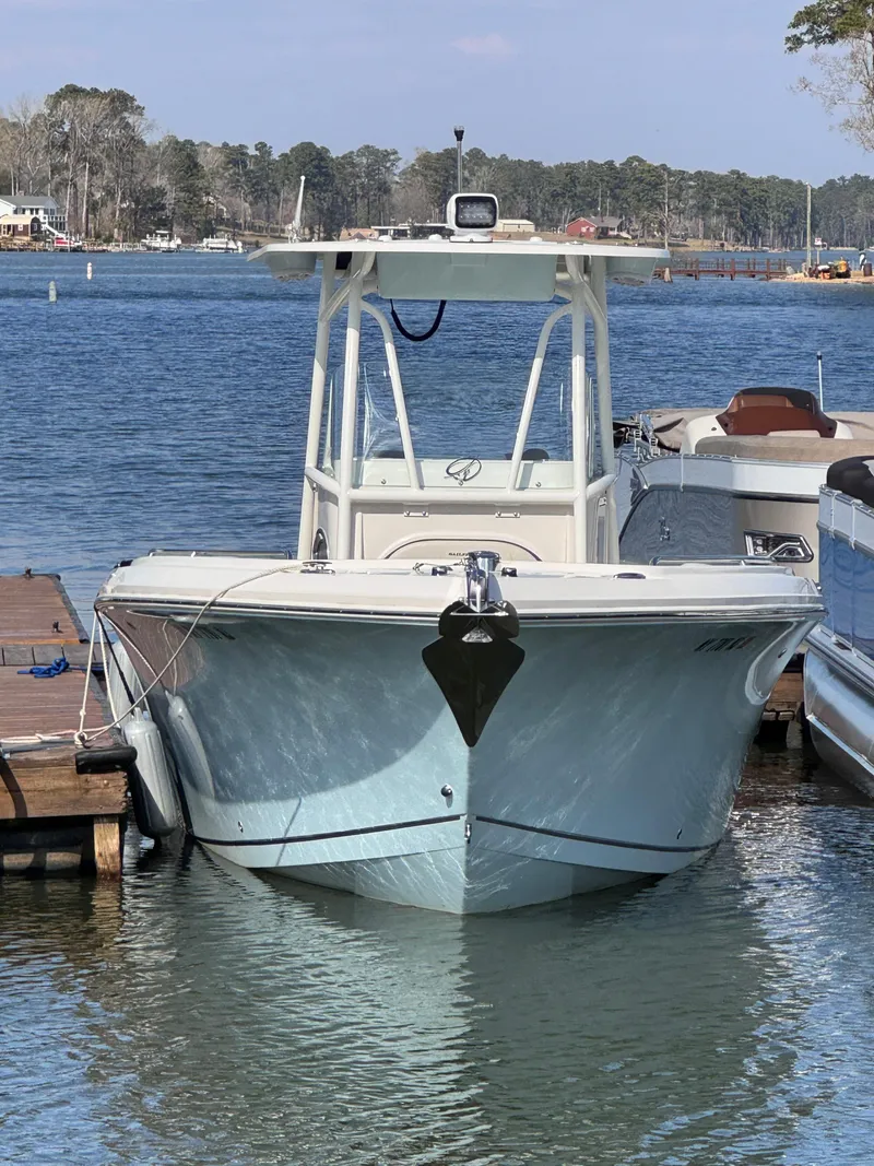 Slide: The Image of 2023 Sailfish 242 CC boat docked on a calm lake with scenic background. - 11