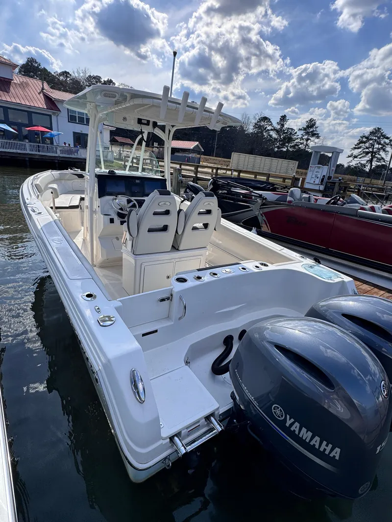 Slide: The Image of 2023 Sailfish 242 CC boat with dual Yamaha engines docked under a cloudy sky. - 2
