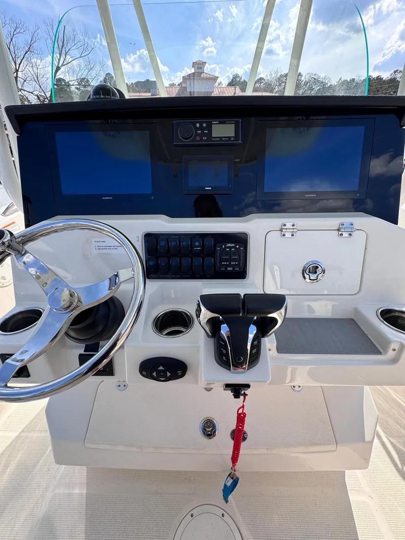 Slide: The Image of 2023 Sailfish 242 CC boat dashboard with steering wheel, controls, and navigation screens. - 6