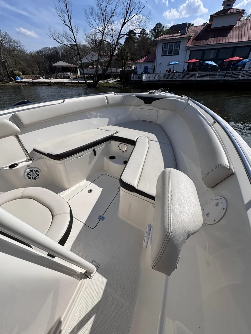 Slide: The Image of 2023 Sailfish 242 CC boat interior with cushioned seating, docked near waterfront buildings. - 8