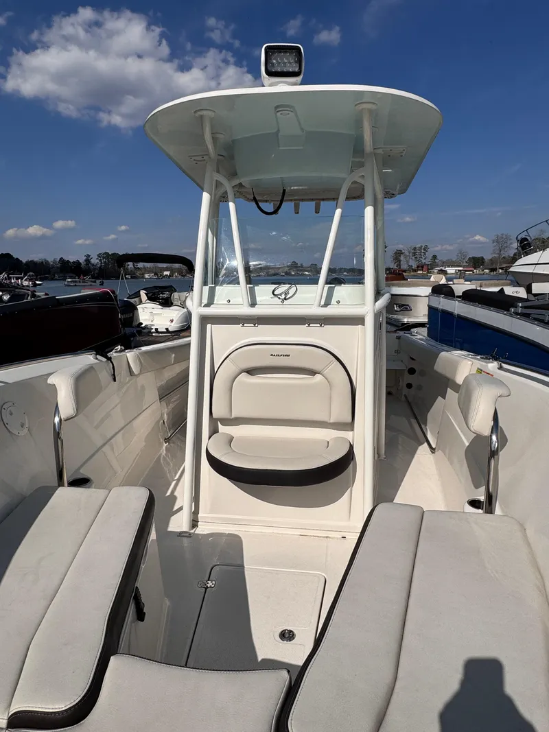 Slide: The Image of 2023 Sailfish 242 CC boat interior with seating and console under clear blue sky. - 9
