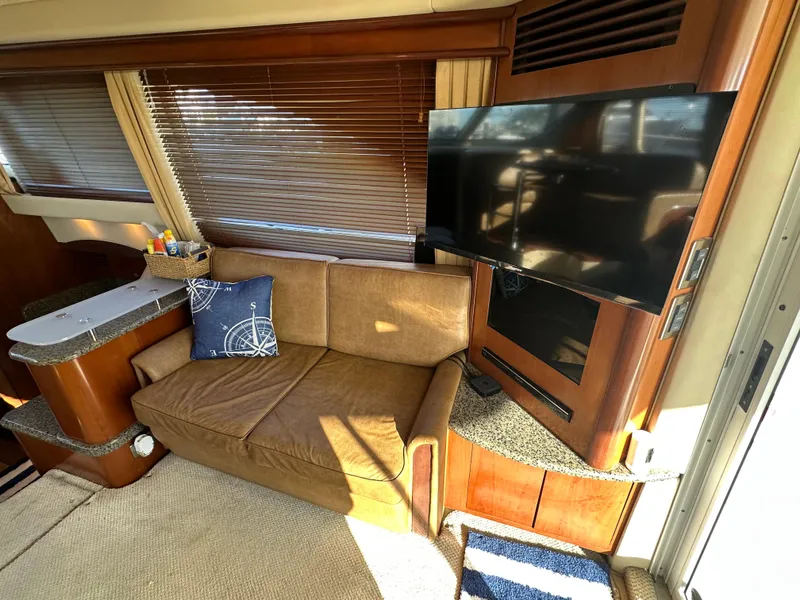 Slide: The Image of Interior of 2005 Sea Ray 420 Sedan Bridge with sofa, TV, and wooden accents. - 13