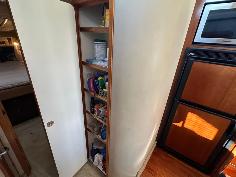 Slide: The Image of Cabinet storage inside 2005 Sea Ray 420 Sedan Bridge yacht, featuring shelves with various items. - 19