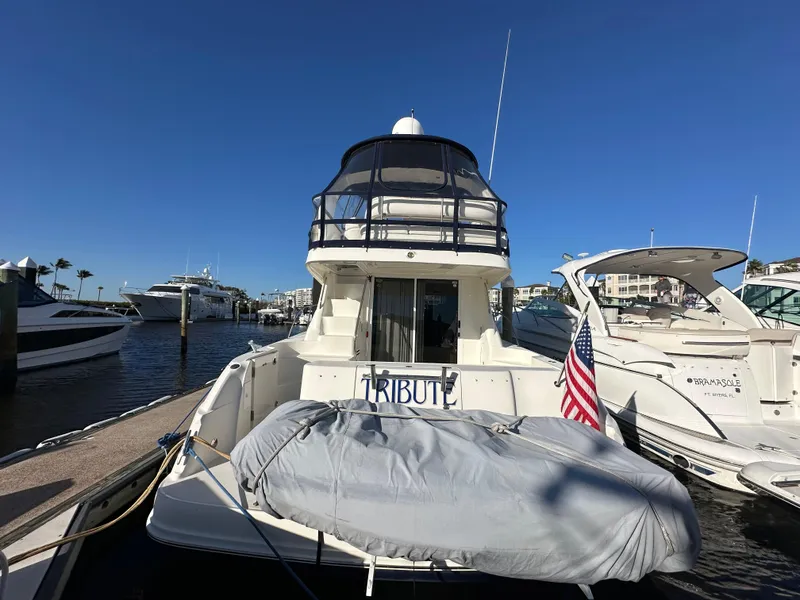 Slide: The Image of 2005 Sea Ray 420 Sedan Bridge yacht docked at marina, rear view with American flag. - 2