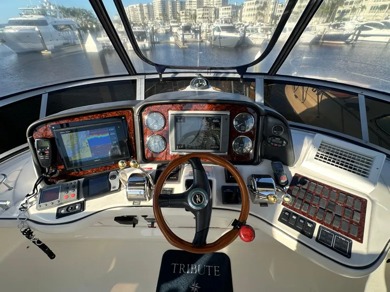 Slide: The Image of 2005 Sea Ray 420 Sedan Bridge helm with navigation screens and controls, docked in a marina. - 8
