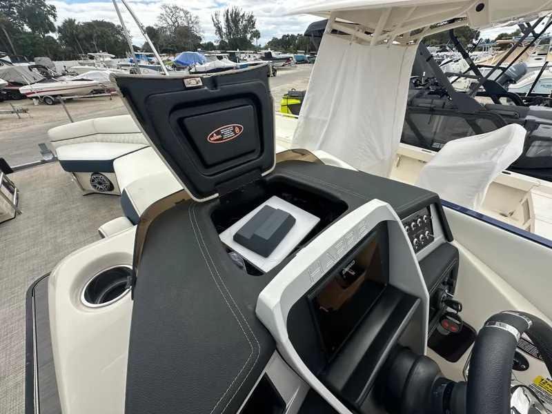 Slide: The Image of 2022 Harris Crowne SL 250 boat dashboard with open storage compartment and seating area. - 22