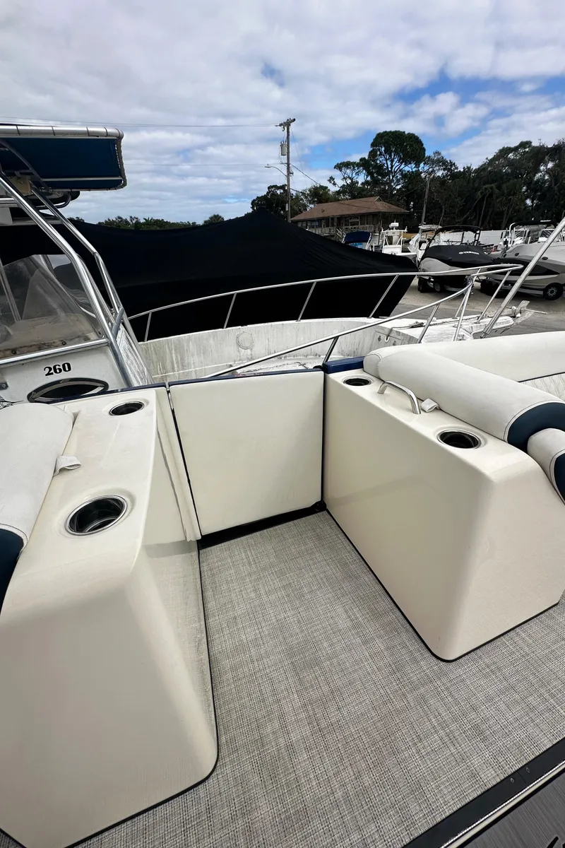 Slide: The Image of 2022 Harris Crowne SL 250 boat interior with seating and cup holders, docked under a cloudy sky. - 29