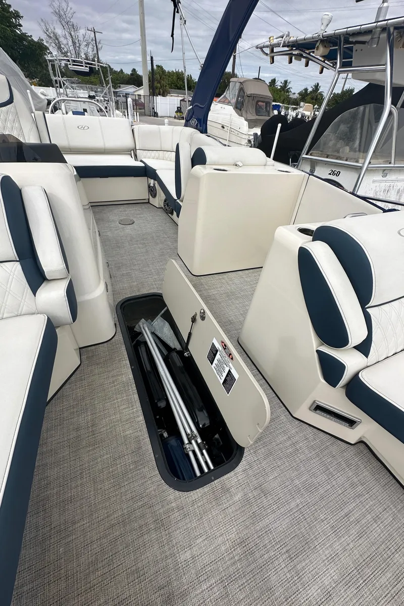 Slide: The Image of 2022 Harris Crowne SL 250 boat interior with open storage compartment and cushioned seating. - 30