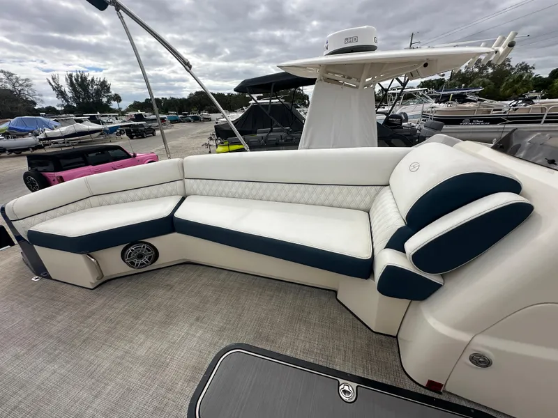 Slide: The Image of 2022 Harris Crowne SL 250 boat interior with white and blue seating, docked under cloudy skies. - 32