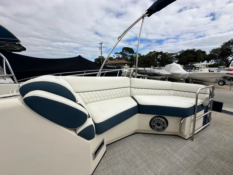 Slide: The Image of 2022 Harris Crowne SL 250 boat with luxurious white and blue seating, docked outdoors. - 36