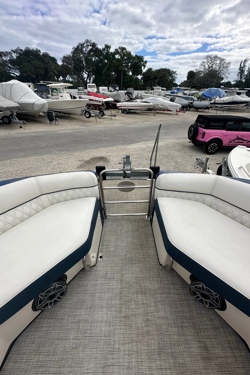 Slide: The Image of 2022 Harris Crowne SL 250 pontoon boat interior with white seating, parked in a marina. - 42