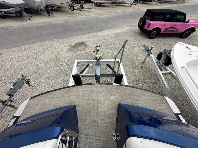 Slide: The Image of 2022 Harris Crowne SL 250 boat on trailer, surrounded by other vehicles and boats. - 43