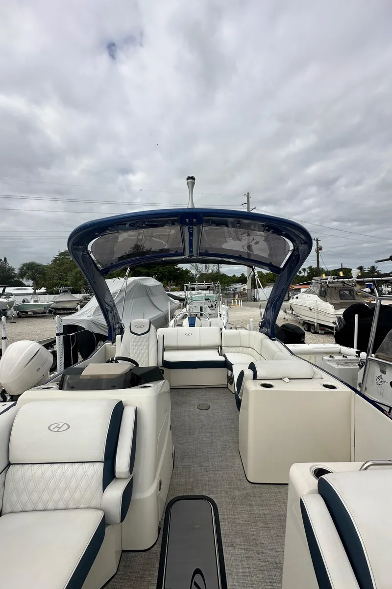 Slide: The Image of 2022 Harris Crowne SL 250 pontoon boat with spacious seating and sleek design at a marina. - 46