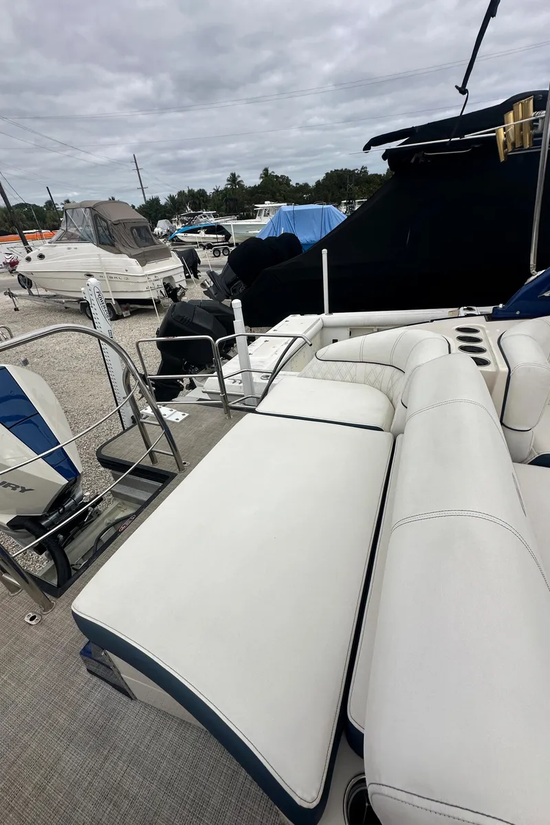 Slide: The Image of 2022 Harris Crowne SL 250 boat with white seating, docked under cloudy skies. - 8