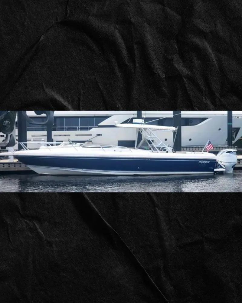 Slide: The Image of 2000 Intrepid 366 boat docked, featuring sleek design and American flag. - 0