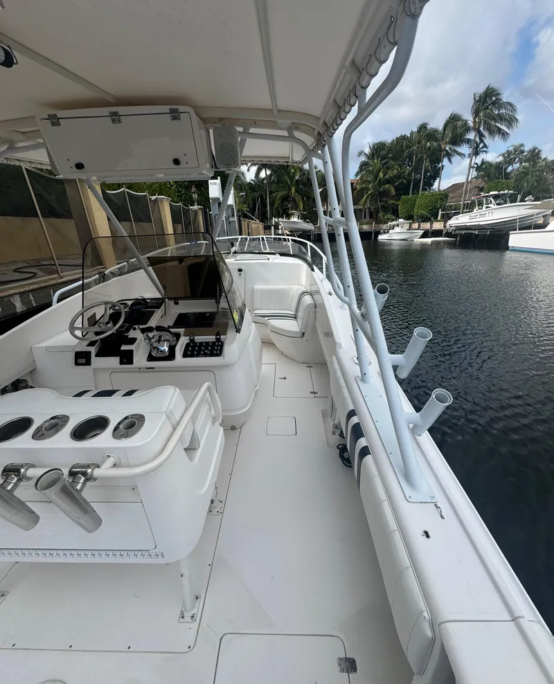 Slide: The Image of 2000 Intrepid 366 boat docked by a canal, featuring a spacious deck and fishing rod holders. - 10