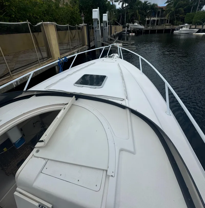 Slide: The Image of 2000 Intrepid 366 boat docked by a canal, featuring sleek white design and spacious deck. - 19