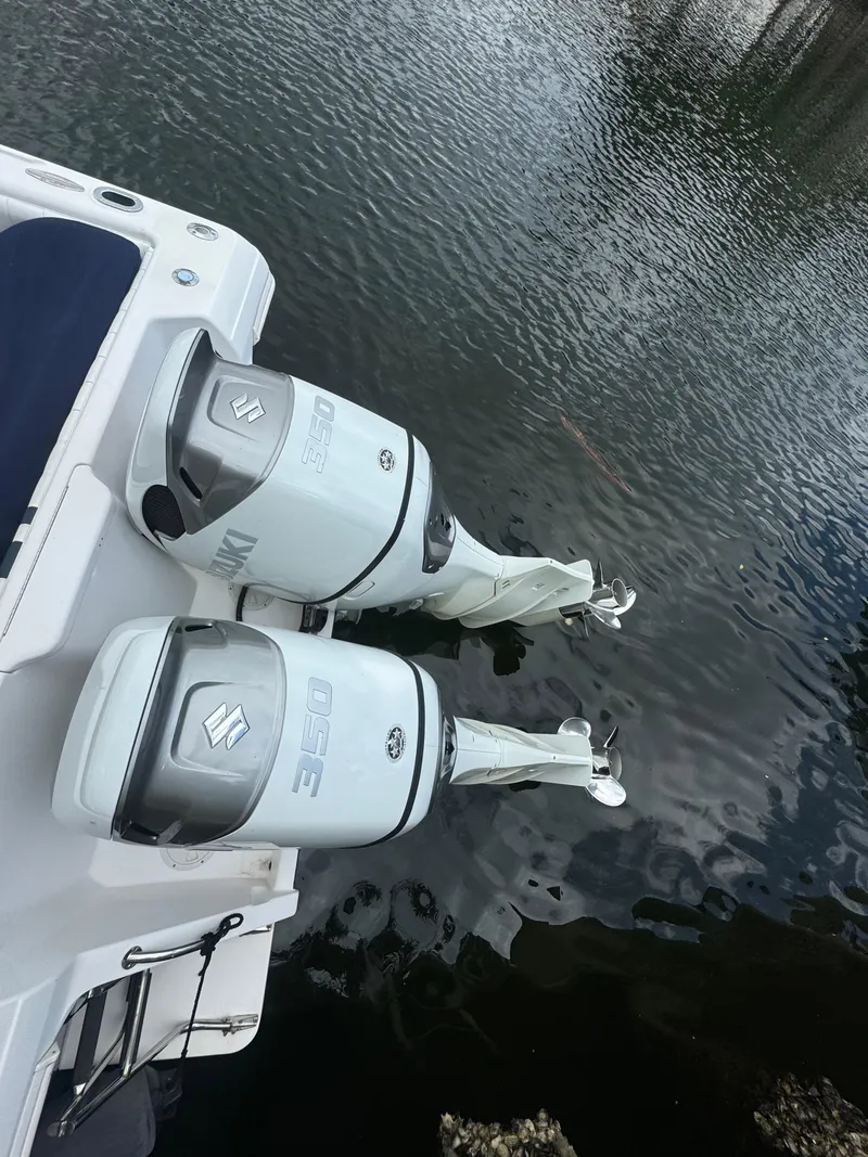 Slide: The Image of Twin Suzuki outboard motors on a 2000 Intrepid 366 boat, docked on calm water. - 2