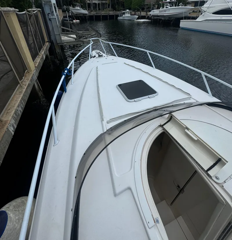 Slide: The Image of 2000 Intrepid 366 boat docked, showing deck and open hatch, surrounded by water and other boats. - 20