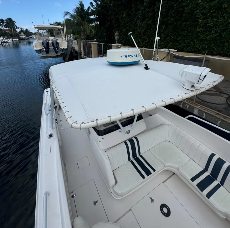 Slide: The Image of 2000 Intrepid 366 boat docked, featuring white seating and canopy, in a serene marina setting. - 21