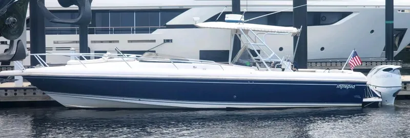 Slide: The Image of 2000 Intrepid 366 boat docked, featuring sleek design and American flag. - 33