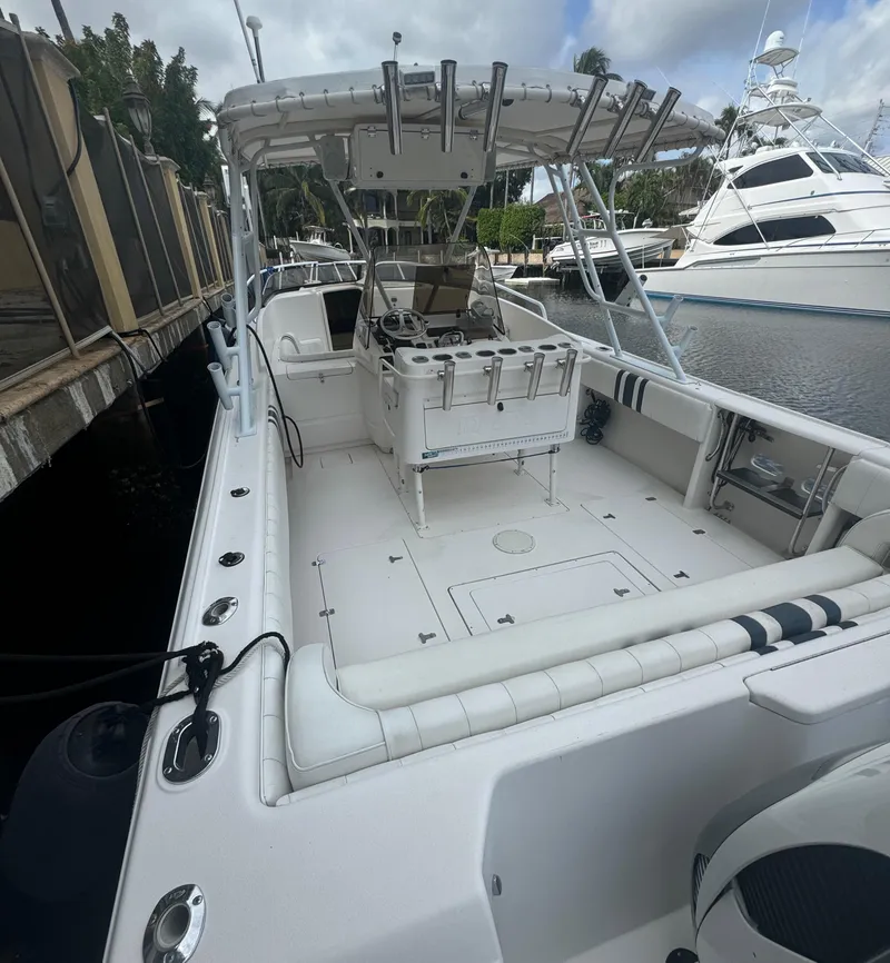 Slide: The Image of 2000 Intrepid 366 boat docked, featuring spacious deck and seating, with fishing rod holders. - 4