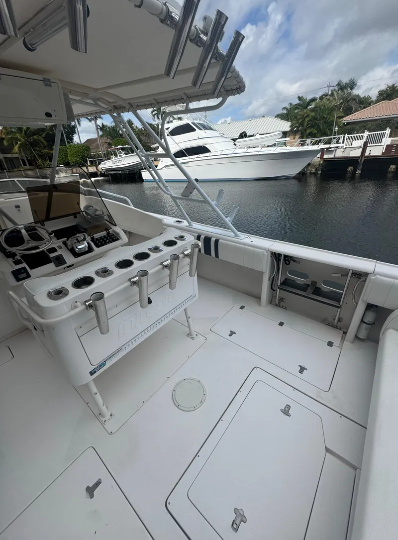 Slide: The Image of 2000 Intrepid 366 boat interior with fishing rod holders, docked near luxury yachts. - 5