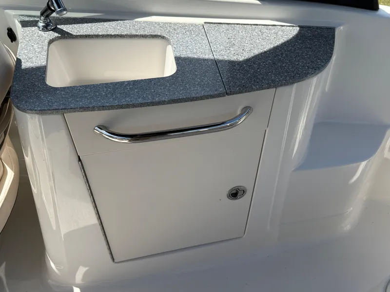 Slide: The Image of 2016 Chaparral 244 boat sink with granite countertop and storage cabinet. - 13
