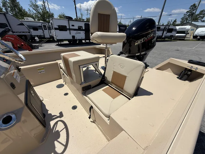 Slide: The Image of 2025 G3 Bay 20 boat interior with seating and motor, parked near RVs. - 5