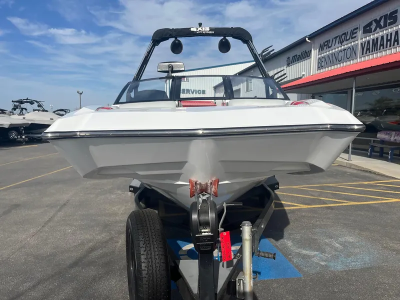 Slide: The Image of 2021 Axis A22 boat on trailer outside dealership, clear sky background. - 11