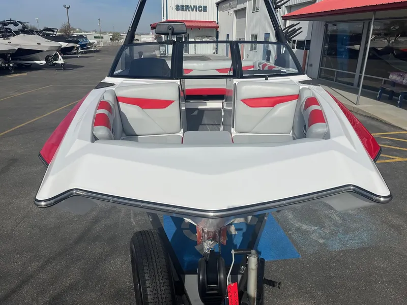 Slide: The Image of 2021 Axis A22 boat with red and white interior, parked at a dealership. - 13