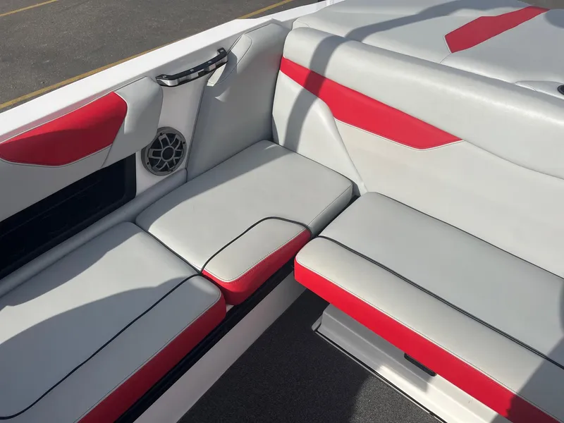 Slide: The Image of 2021 Axis A22 boat interior with red and gray seating, featuring a speaker and handle. - 22